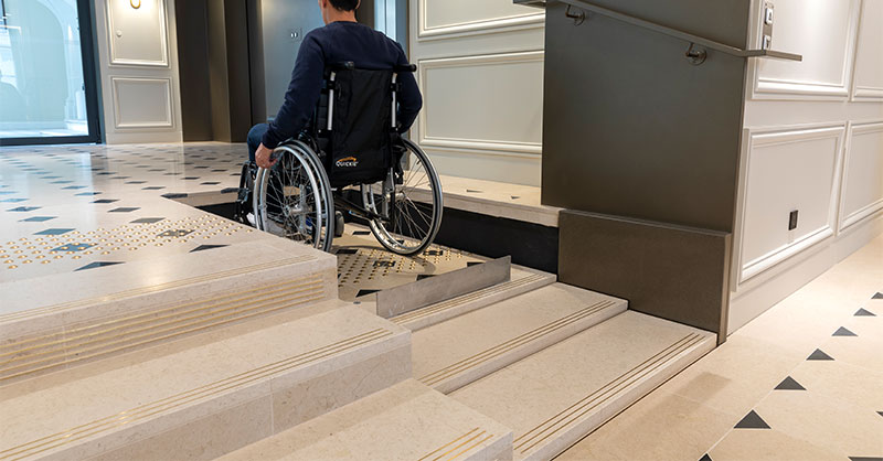 Rollstuhlfahrer auf Lifttreppe als Hebebühne
