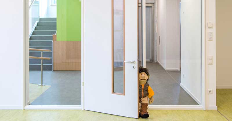 Puppe an einer geöffneten Tür zum Treppenhaus