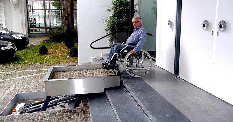 Mann im Rollstuhl fährt auf den Schräglift