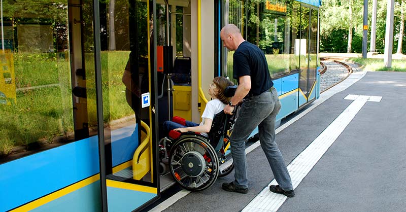 Fahrer hilft Rollifahrerin beim Einstieg in die Straßenbahn