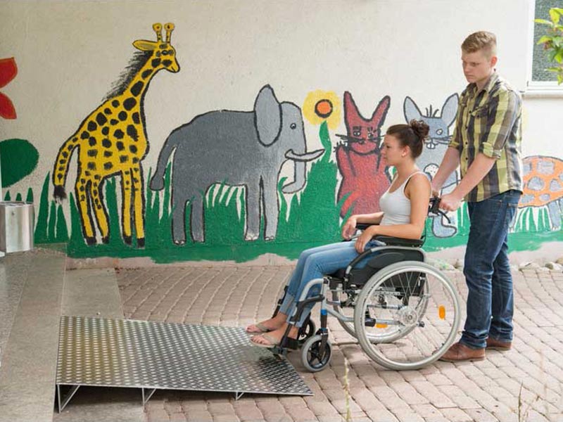 Ein Junge schiebt ein Mädchen im Rollstuhl über die Keilbrücke