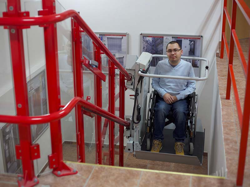 ein Rollstuhlfahrer wird mit dem Treppenplattformlift befördert