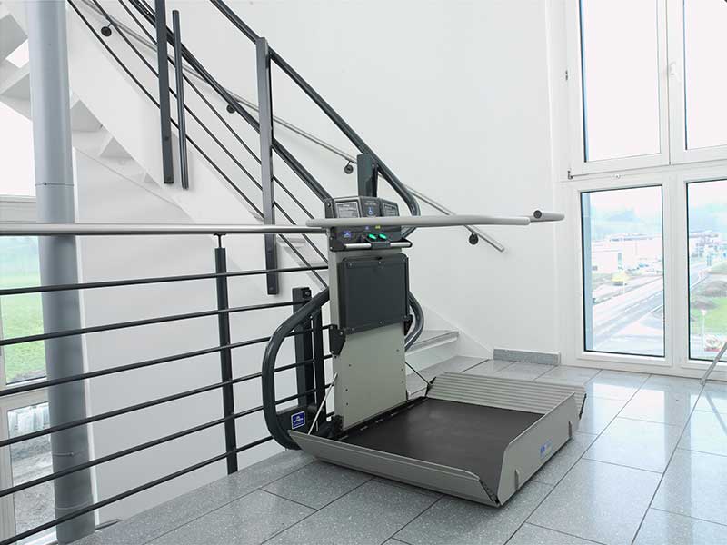 Treppenplattformlift für Rollstuhl mit Auffahrklappe am Treppenabsatz in einem Gebäude