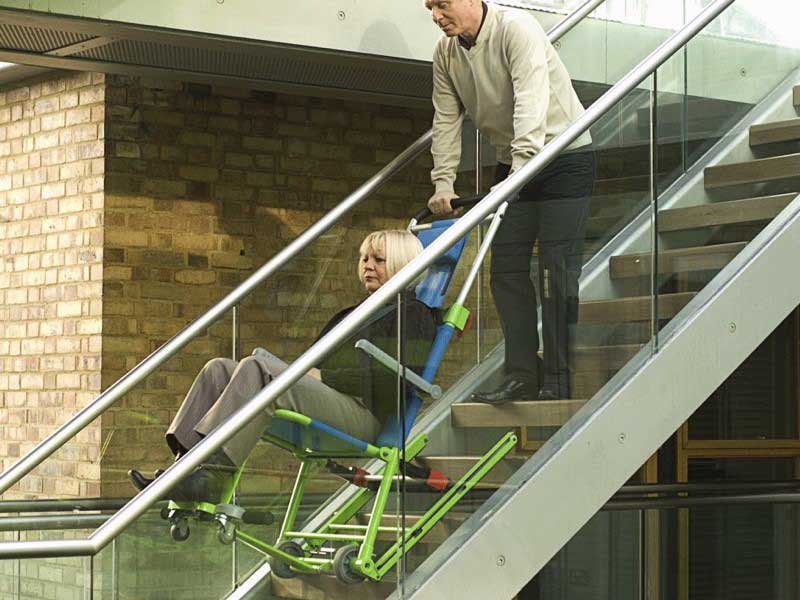 Eine Frau wird im Rettungsstuhl eine Treppe hinunter befördert.