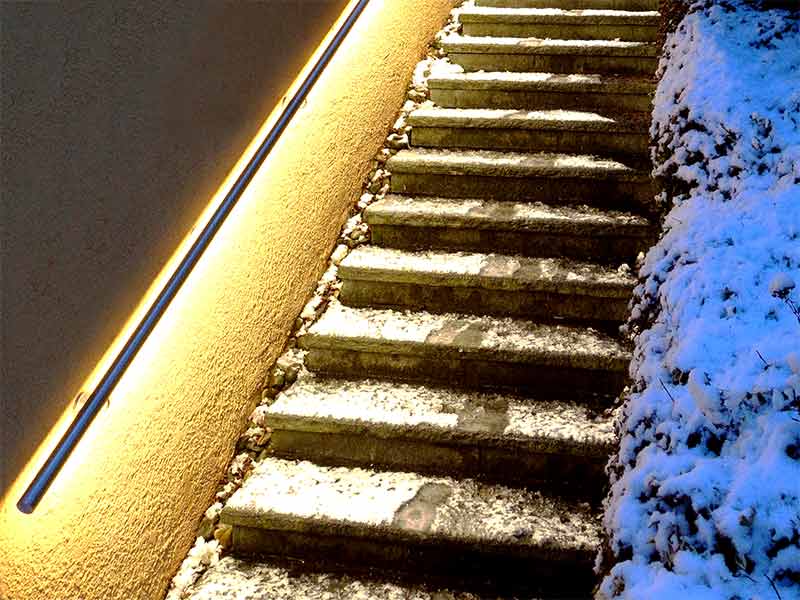 beleuchteter Handlauf an einer schneebedeckten Treppe
